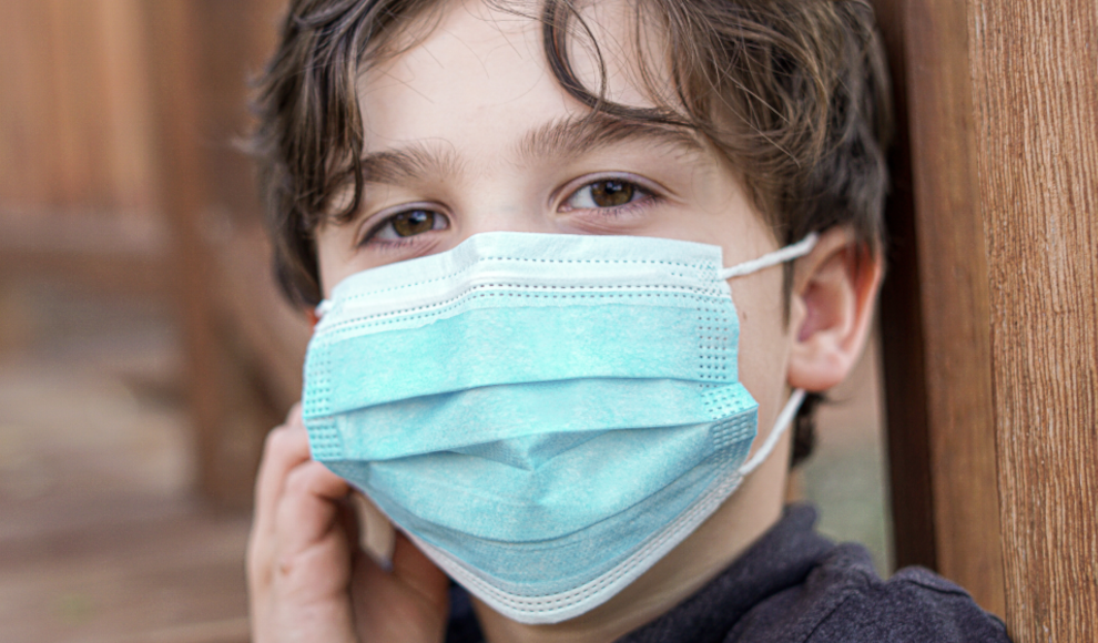 Kind mit Maske zum Schutz vor SARS-CoV-2